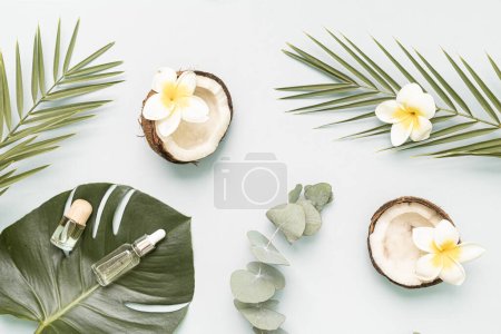 Photo for Bamboo toothbrush and bootle essential oil on a table with copy space on a white background. Styled composition of flat lay with tropical leaves and flowers - Royalty Free Image