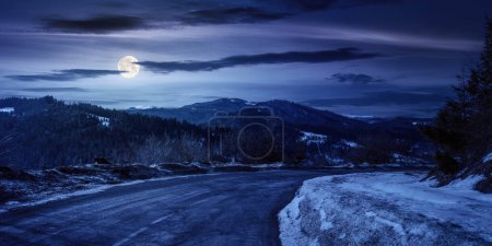 Photo for Uzhanian pass in winter at night. old country road through mountains. beautiful countryside scenery with forested hills in full moon light - Royalty Free Image