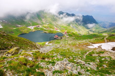 alpine Landschaft der Fagaras-Berge. balea See in Rumänien im Sommer. bewölkt bei trübem Licht. Flecken von Schnee und Gras an den felsigen Hängen der Karpaten