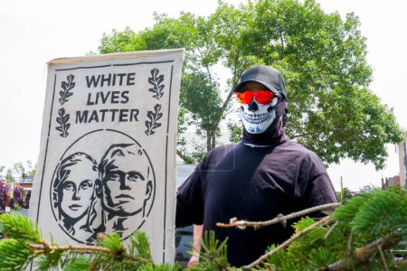 Foto de HUDSON, WI, USA - 17 DE JUNIO DE 2023: Individuo enmascarado no identificado sosteniendo la bandera de White Lives Matter en la celebración del Orgullo de Hudson. - Imagen libre de derechos