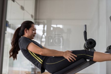 Téléchargez les photos : Sporty Asiatique jeune femme faisant des redressements assis au gymnase de remise en forme. Carrosserie et mode de vie sain concept. - en image libre de droit