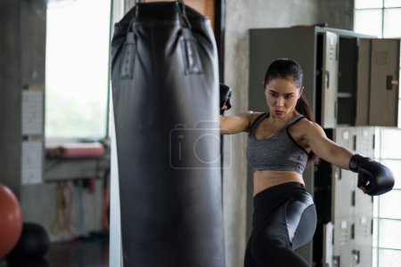 Téléchargez les photos : Forte femme de boxe asiatique coup gros sac de boxe à la salle de fitness. Athlétique fille formation Muay Thai pour la musculation et mode de vie sain concept. entraînement dans le club de sport. - en image libre de droit