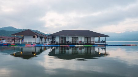 Foto de Floating homestay resort with skyline reflection on lake at dawn in Srinakarin or Srinagarind Dam, Kanchanaburi, Thailand. Famous travel at summer in tropical country, Siam. - Imagen libre de derechos