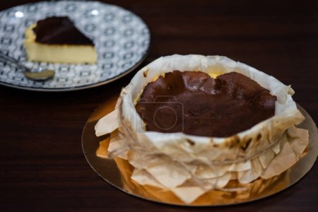 Téléchargez les photos : Basque burnt cheesecake with blur piece of cut spanish dessert in dish on brown wooden table - en image libre de droit