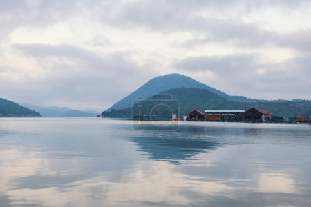 Téléchargez les photos : Maison flottante séjour station avec reflet skyline sur le lac en face de la montagne le matin à Srinakarin ou Srinagarind Dam, Kanchanaburi, Thaïlande. Célèbre voyage en été dans les pays tropicaux, Siam. - en image libre de droit
