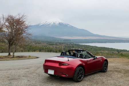 Photo for Red open sunroof car parking at Yamanakako Panorama Dai viewpoint with mount Fuji view, Lake Yamanaka, Yamanashi, Japan. Famous travel destination of 5 lakes Fujisan. - Royalty Free Image