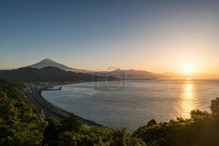 Photo for Mount Fuji and highway street by the bay seen from Satta Toge pass at sunrise with reflection on sea, Shimizu, Shizuoka, Japan. Famous photography top view spot for tourist people. - Royalty Free Image