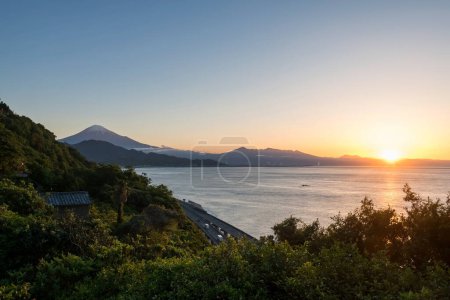 Photo for Mount Fuji and street by bay seen from Satta Toge pass at sunrise with reflection on sea, Shimizu, Shizuoka, Japan. Famous photography top view spot for tourist people. - Royalty Free Image