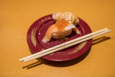 Foto de Salmón tobiko sushi en plato rojo con palillos en el restaurante japonés. Tradicional famosa comida japonesa. - Imagen libre de derechos