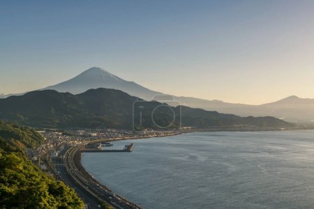 Photo for Mount Fuji and curve highway street by bay seen from Satta Toge pass at sunrise on sea, Shimizu, Shizuoka, Japan. Famous photography top view spot for tourist people. - Royalty Free Image