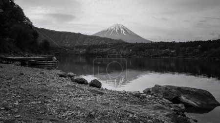 Photo for Landscape of mt.Fuji and floating boat on Lake Saiko in morning with skyline reflection, Yamanashi, Japan. Famous travel destination and holiday vacation maker. Black and white photo. - Royalty Free Image