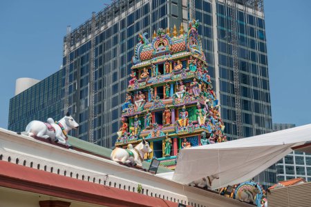 Téléchargez les photos : Belle statue sculptée sur tour au Sri Mariamman Temple contre bâtiment moderne, Singapour. Cette célèbre destination touristique située à Chinatown est le plus ancien temple hindou de Singapour.. - en image libre de droit
