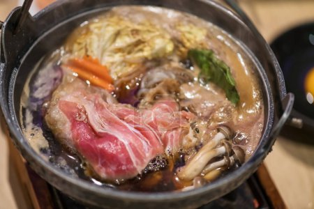 Photo for Japanese Suki Yaki or shabu soup on hot pot in reestaurant. Closeup at fresh pork by top view. - Royalty Free Image