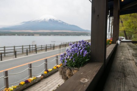 Photo for Purple flower decor on cafe wooden balcony by lake Yamanakako with mount Fuji view, Yamanashi, Japan. Coffee shop and restaurat by the lake - Royalty Free Image