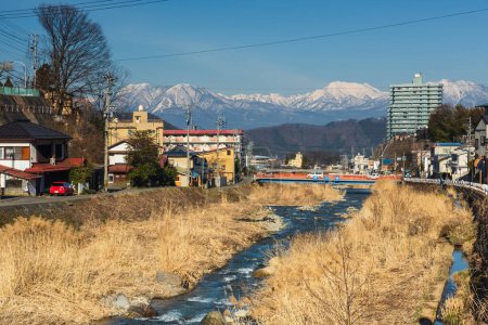 Foto de La ciudad de Shibu onsen y los alpes centrales se montan contra el cielo azul, Yamanouchi, Nagano, Japón. La ciudad es famosa por las aguas termales y el parque de nieve de monos Jigokudani - Imagen libre de derechos