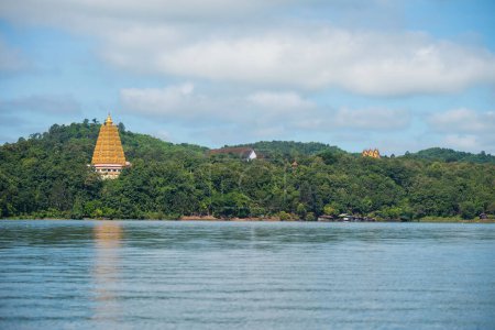 Bodhgaya golden pagoda and local raft village by hill forest against blue sky and cloud in Sangkhlaburi, Kanchanaburi, Thailand. Famous travel destination and holiday maker in Siam.