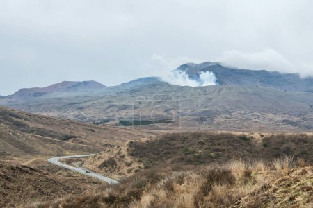 Car drive on road to visit mount Aso volcano with heavy smoke, Kumamoto, Kyushu, Japan. Here is the largest active volcano in Japan. Beautiful landscape and famous travel destination.