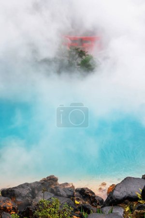 Umi Jigoku Sea Hell or cobalt blue pond of Kamado Jigoku and heavy steam and red torii gate, Beppu, Oita, Japan. Famous travel destination and one of the most famous photogenic of the eight hells.
