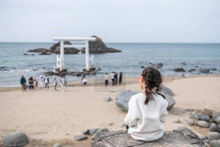 Parte trasera de la chica japonesa ver Sakurai Futamigaura par de piedras y torii blanco puerta en Itoshima, Prefectura de Fukuoka, Japón. Uno de los destinos turísticos más famosos de Itoshima.