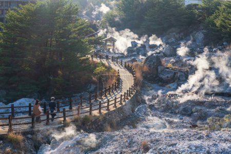 Menschen gehen bergab, um das Höllental Jigoku am Berg Unzen onsen heißen Quellen bei Sonnenuntergang von Shimabara, Nagasaki, Kyushu, Japan zu besuchen. Heißes Wasser, Schwefelgase und Dampf sprudeln aus vulkanischem Quellfeld.