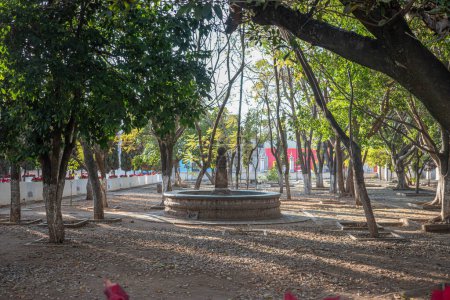 Foto de OCOTLN DE MORELOS, OAXACA, MXICO- 19 DE ENERO DE 2023: Vista del jardín del Convento de Santo Domingo de Guzmn con una fuente en medio y árboles en un día soleado en Ocotln de Morelos, Oaxaca - Imagen libre de derechos