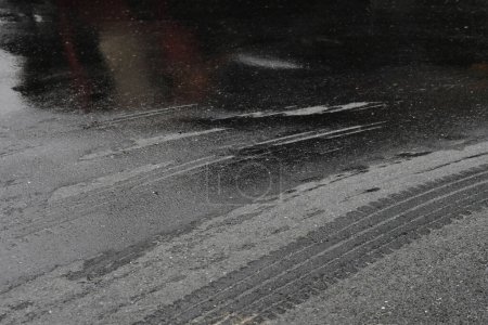 Nasses Auto auf einer schwarzen Asphaltstraße. abstrakte Textur