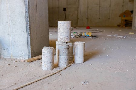 Téléchargez les photos : Quelques piliers cylindriques en béton placés sur le plancher du bâtiment en construction percés pour des tests de qualité. - en image libre de droit