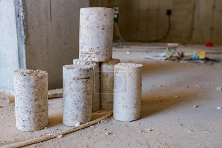 Téléchargez les photos : Quelques piliers cylindriques en béton placés sur le plancher du bâtiment en construction percés pour des tests de qualité. - en image libre de droit