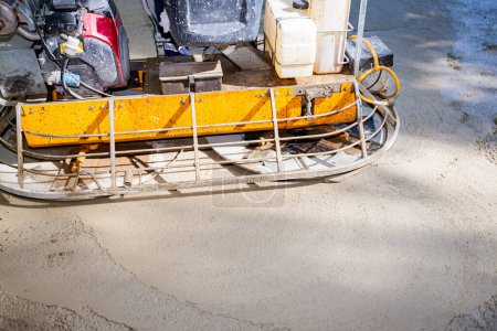 Photo for Close-up of self-leveling power trowel machine, for smoothing surface on concrete slab. Worker sitting on a machine with gas engine has wheels with pads, plate and he is driving it in circles. - Royalty Free Image