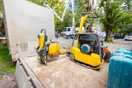 Photo for Small plate compactor, standing vibratory hammer and jumping jack tamping machine was placed on the truck trailer. Power tools at construction site. - Royalty Free Image