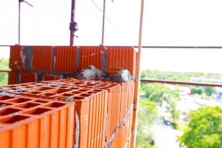 Foto de Mason, albañil trabajador está utilizando bloques rojos para montar una pared al lado de la línea de cuerda para ser recta. - Imagen libre de derechos
