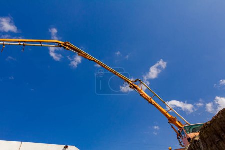 Photo for Truck with pump machine is standing on the edge, cliff of ground, directing exit tube on right direction to bridge foundation, construction site. - Royalty Free Image