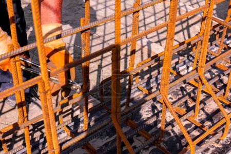 Photo for Worker is tying rebar with wire using pliers, to make a reinforcing frame for concrete beam. Works on construction site - Royalty Free Image