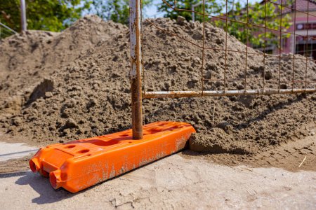 Photo for Hollow plastic fence foot is for stability of temporary metal wire fence panels, installed in front of building site next to the street. - Royalty Free Image