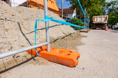 Photo for Hollow plastic fence foot is for stability of temporary metal wire fence panels, installed in front of building site next to the street. - Royalty Free Image