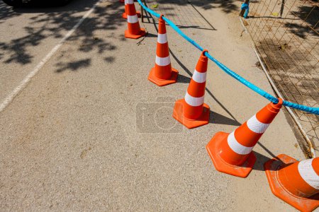 Téléchargez les photos : Plusieurs cônes de circulation orange avec des bandes fluorescentes blanches sont sur la route pour pointer pour alerter et détourner la circulation, signe avec la frontière sont des symboles de prudence. - en image libre de droit