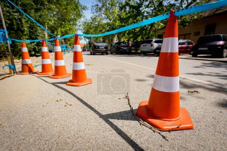 Téléchargez les photos : Plusieurs cônes de circulation orange avec des bandes fluorescentes blanches sont sur la route pour pointer pour alerter et détourner la circulation, signe avec la frontière sont des symboles de prudence. - en image libre de droit