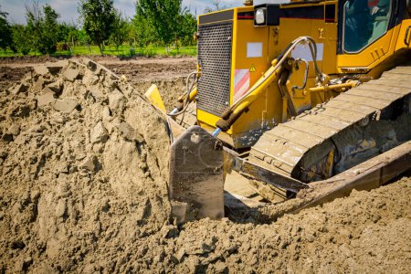 Photo for Close up view on bulldozer undercarriage during pushing, leveling sand for road foundation at building site. - Royalty Free Image