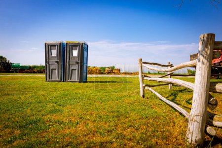 Téléchargez les photos : Deux toilettes mobiles en plastique, rue publique transportable placée à la ferme, ranch avec enclos à chevaux. - en image libre de droit
