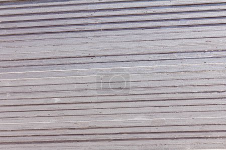 Primer plano de muchas láminas artificiales grises apiladas de madera contrachapada para obras de construcción o decoración de interiores.