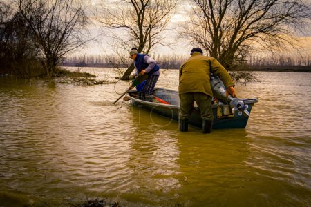 Menschen auf Bootsfahrt auf breitem Fluss, der Waldboden in Küstennähe überflutet hat, Landschaft mit Wasserfluten.