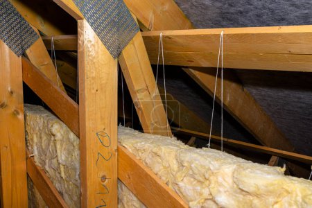 Photo for Insulation of walls and ceiling in the attic made of mineral wool between trusses, tied with polypropylene string. - Royalty Free Image