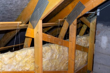 Téléchargez les photos : Isolation des murs et du plafond dans le grenier en laine minérale entre les fermes, liée par une ficelle de polypropylène. - en image libre de droit