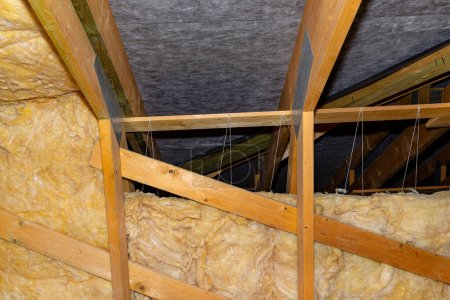 Photo pour Isolation des murs et du plafond dans le grenier en laine minérale entre les fermes, liée par une ficelle de polypropylène. - image libre de droit