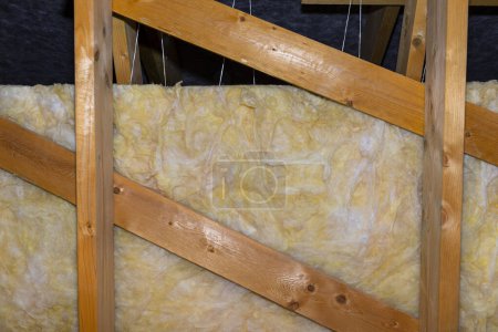 Photo for Insulation of walls and ceiling in the attic made of mineral wool between trusses, tied with polypropylene string. - Royalty Free Image