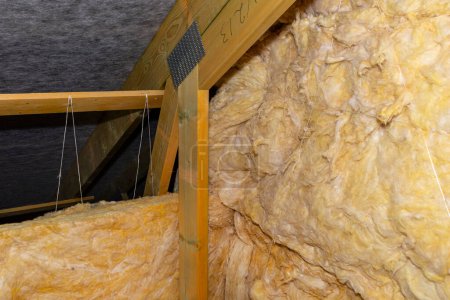 Foto de Aislamiento de paredes y techo en el ático de lana mineral entre cerchas, atado con hilo de polipropileno. - Imagen libre de derechos