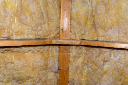 Téléchargez les photos : Isolation des murs et du plafond dans le grenier en laine minérale entre les fermes, liée par une ficelle de polypropylène. - en image libre de droit