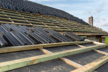 Photo for Roof ceramic tile arranged in packets on the roof on roof battens. Preparation for laying tiles on a boarded roof. - Royalty Free Image