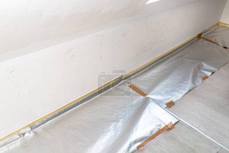 Photo for Dirty wall in various shades of white prepared for painting, the floor is covered with foil. - Royalty Free Image