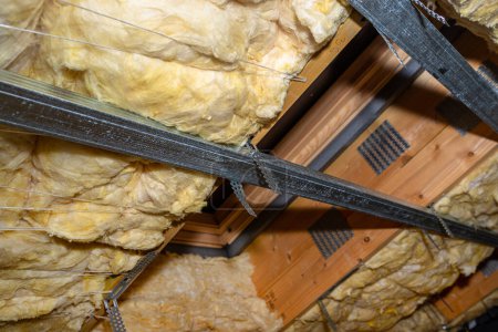Téléchargez les photos : Aluminum frame with hangers placed on beams in the attic for mounting plasterboards, visible roof window. - en image libre de droit